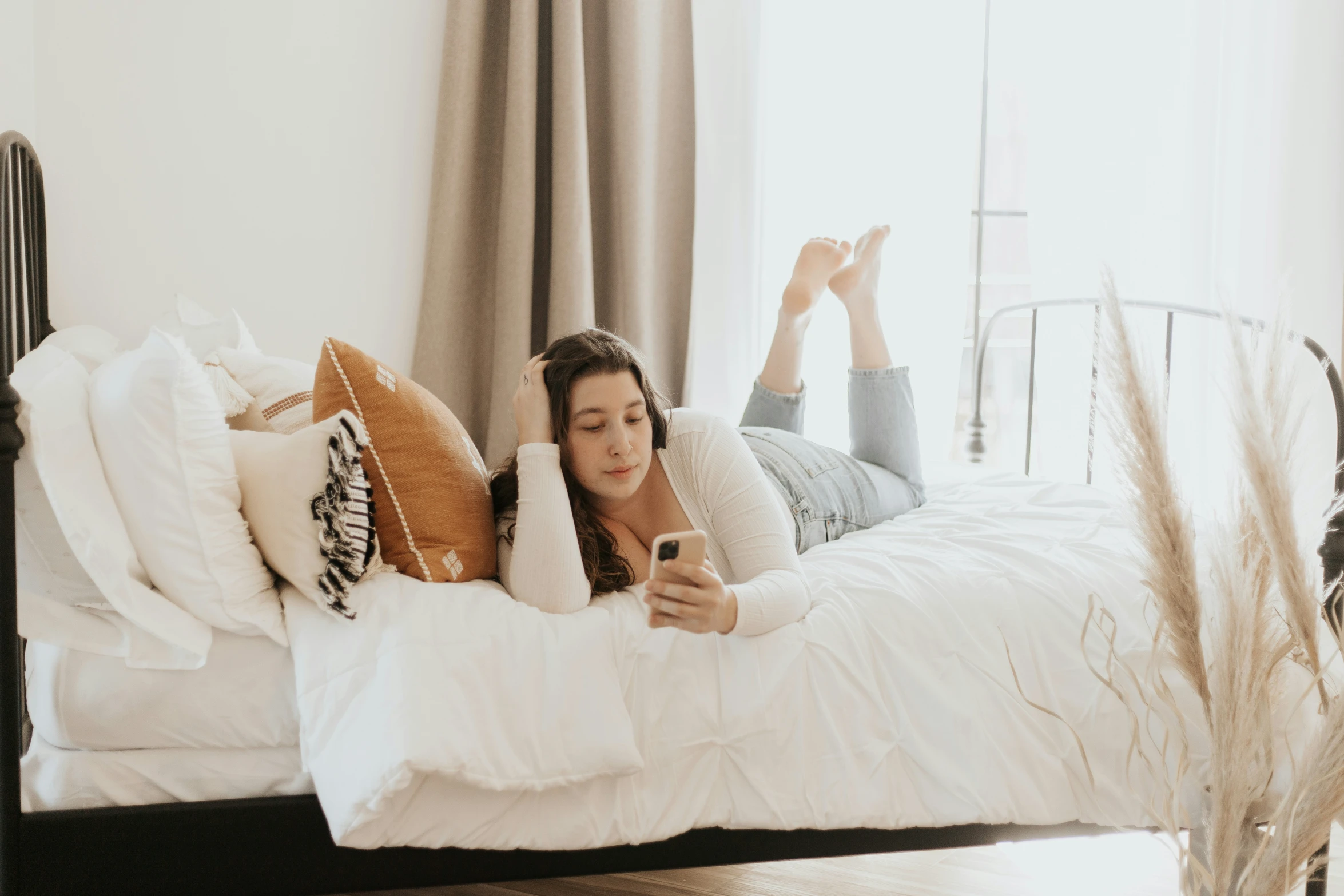 a woman is laying in her bed on her cell phone