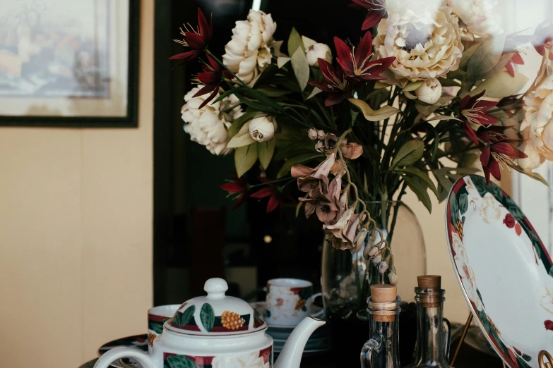 a vase filled with flowers next to two teapots