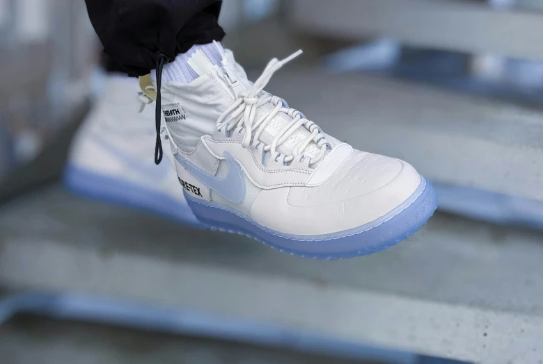 a person standing on concrete steps wearing white and blue shoes