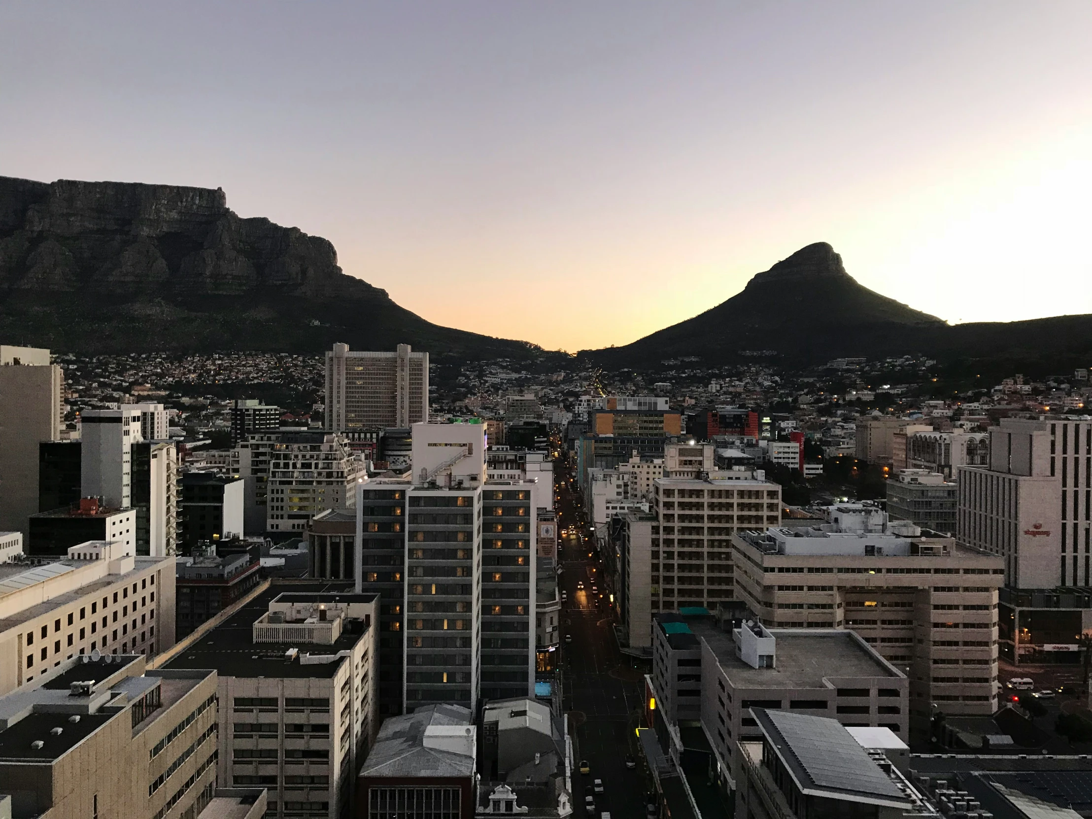 a city at dusk with a mountain in the background