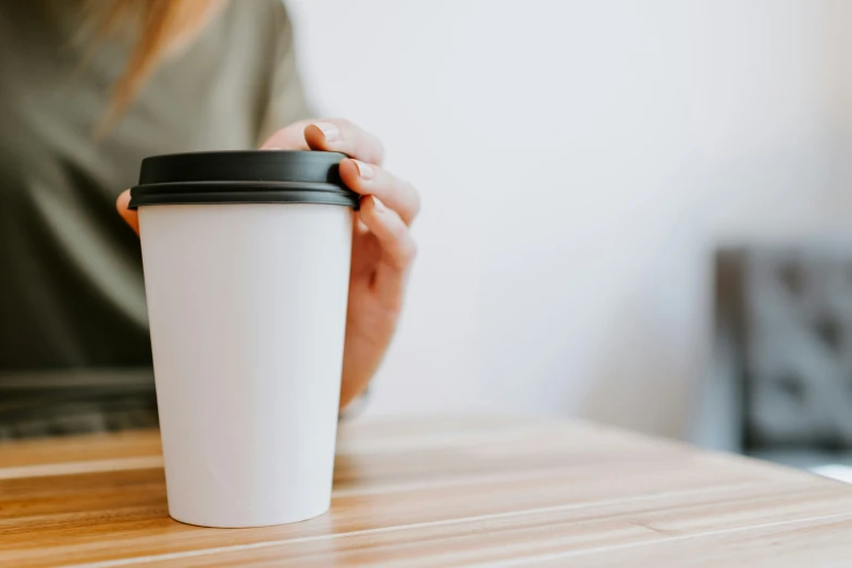 a person holding a coffee cup over a wooden table