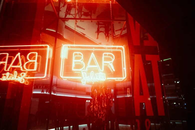 two neon signs over a bar at night