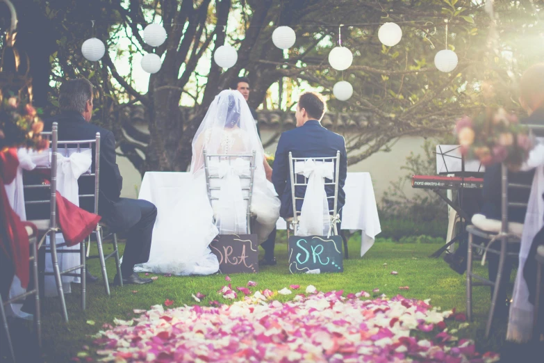 a couple sitting at a table while the bride and groom read their vows