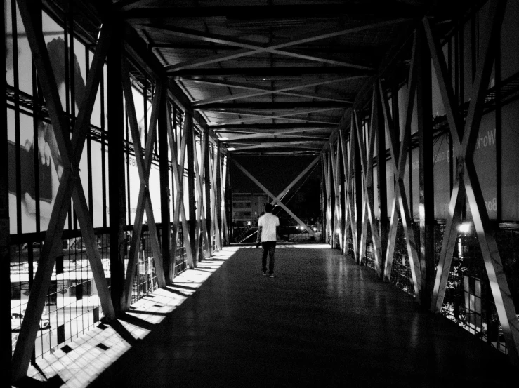 a man walks down a bridge between two buildings