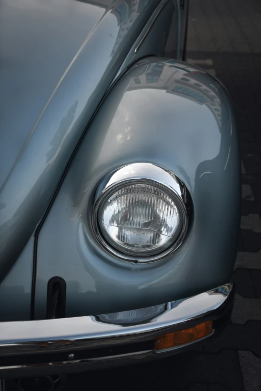 the front view of a grey vw bug sitting in a parking lot
