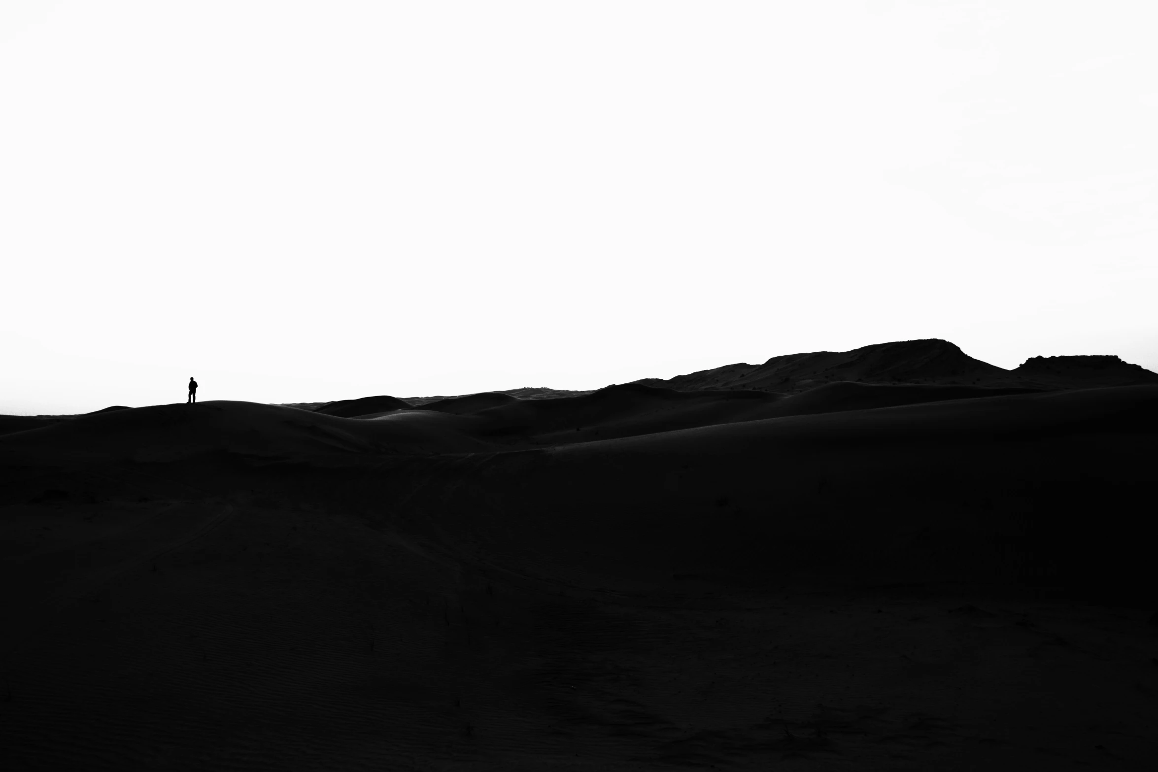 a lone figure standing on the top of a sand dune