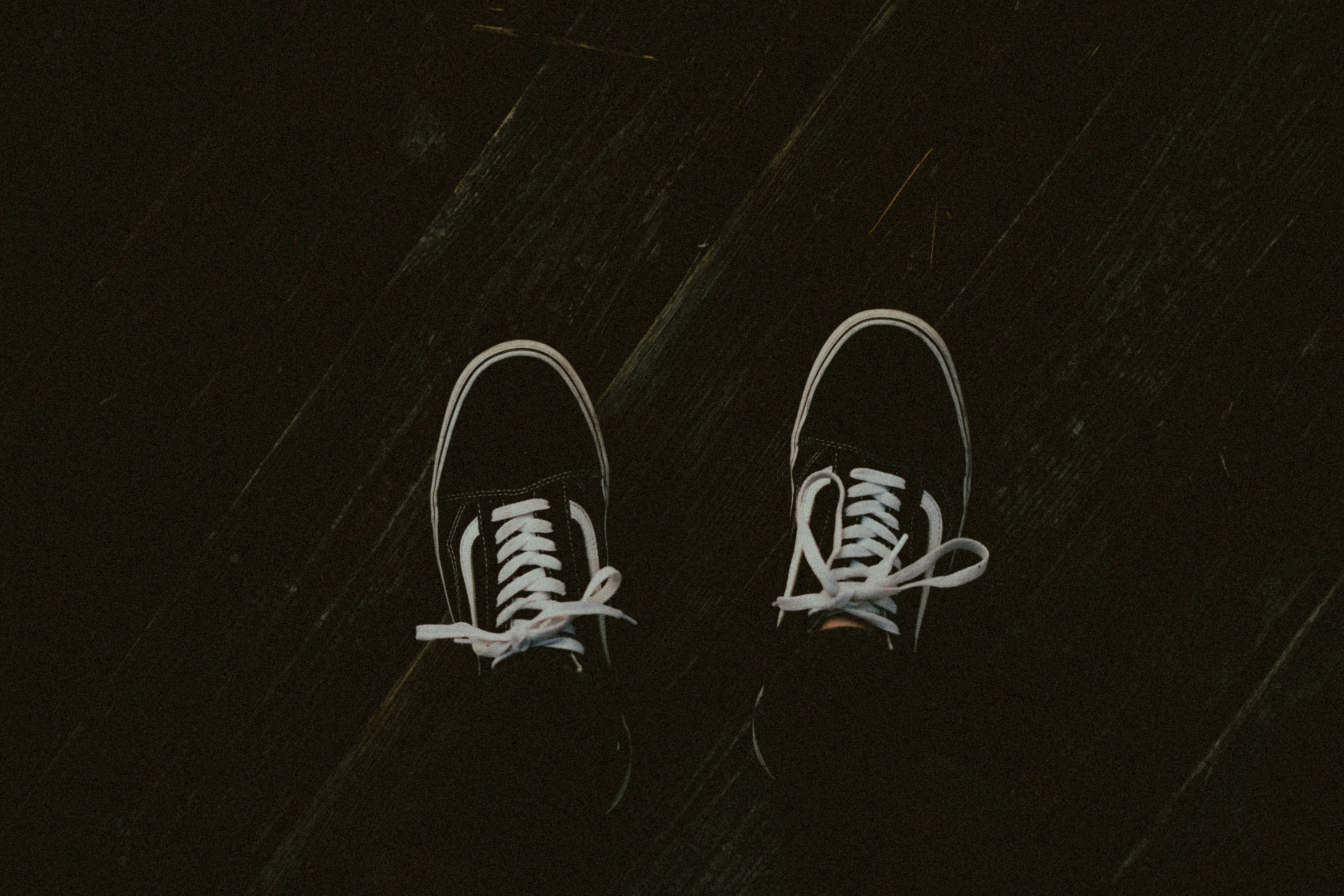 two tennis shoes on black ground, one has a white lace