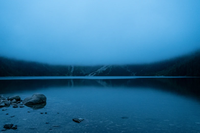 water with rocks on it and a fogy sky