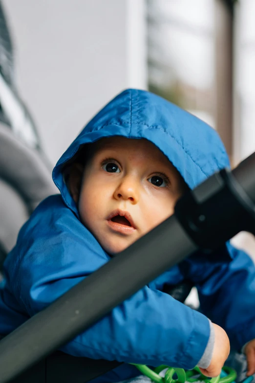 the small baby is in his blue rain jacket