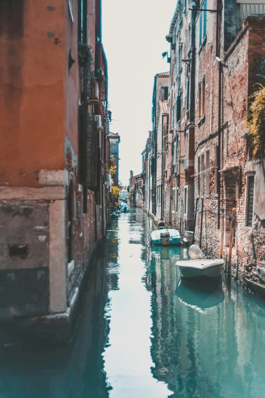 a river runs through a narrow city filled with brick buildings