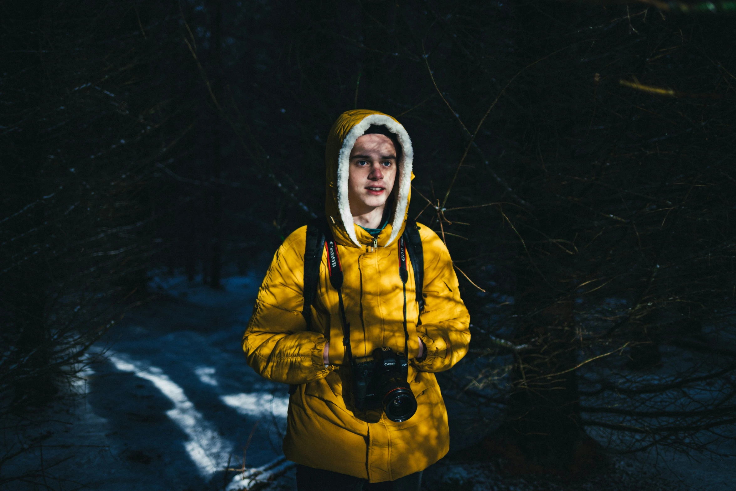 man in yellow jacket on snow covered path in forest