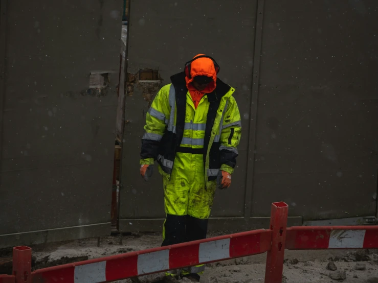 the man in yellow jacket stands near a fence