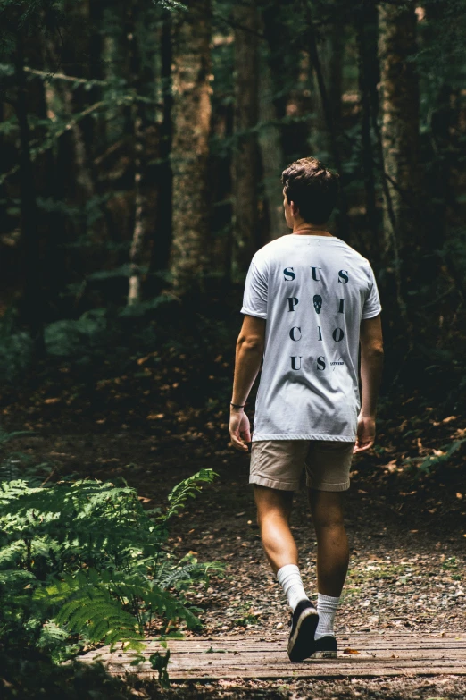 there is a young man walking across a boardwalk in the woods