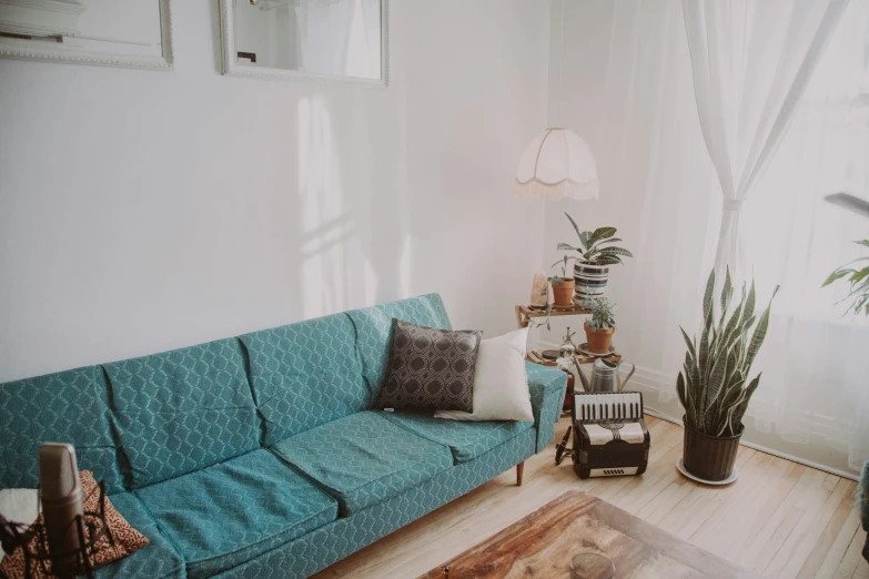 a green couch in front of a window in a living room