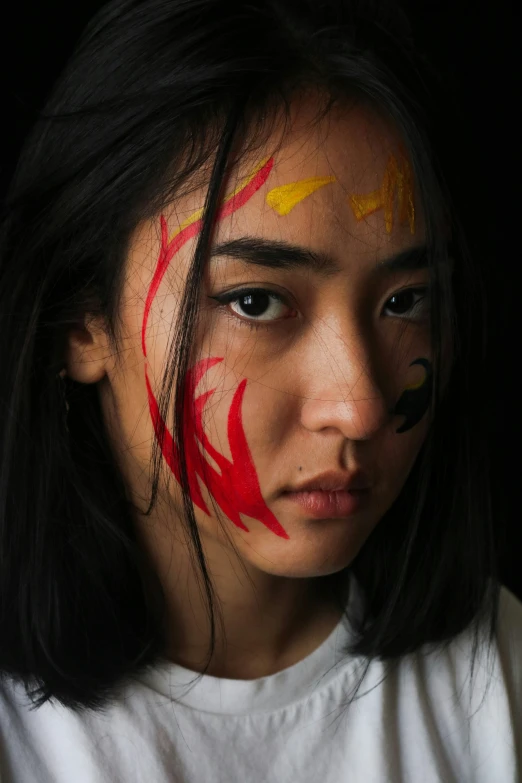 a woman with red paint on her face with a black background