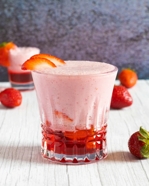 two drinks and strawberries sitting on a table