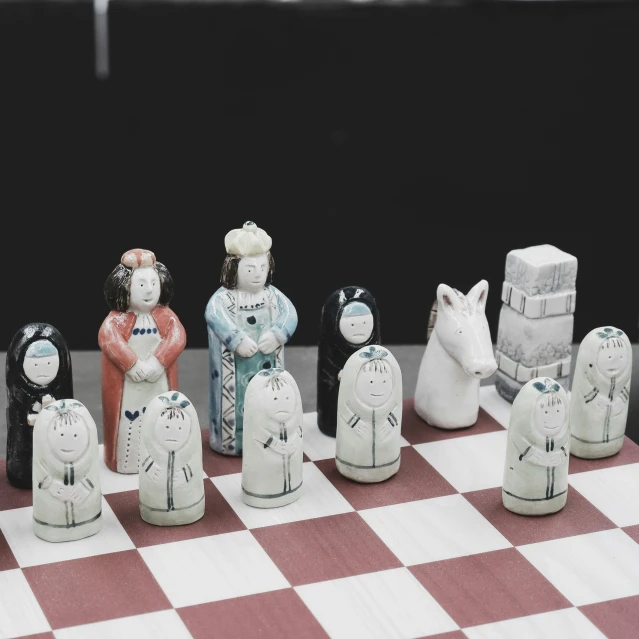 several carved ceramic animals sitting on top of a chess board