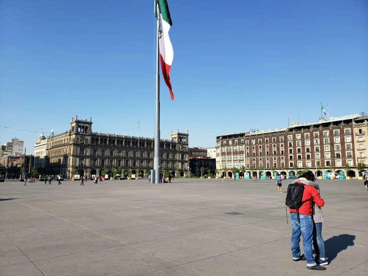 two people standing by a italian flag pole