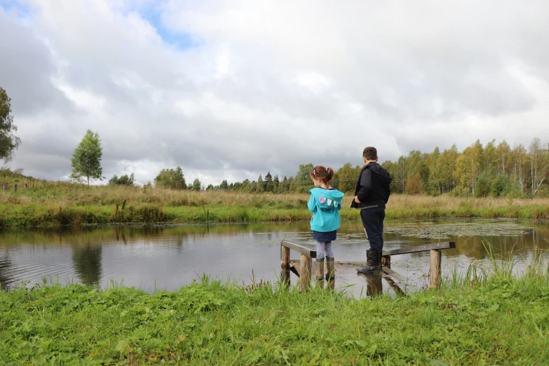 a man and woman standing on wooden beams on the water shore