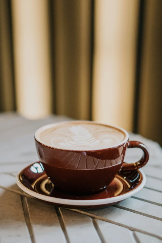 a cappuccino sits atop a saucer, on top of a table