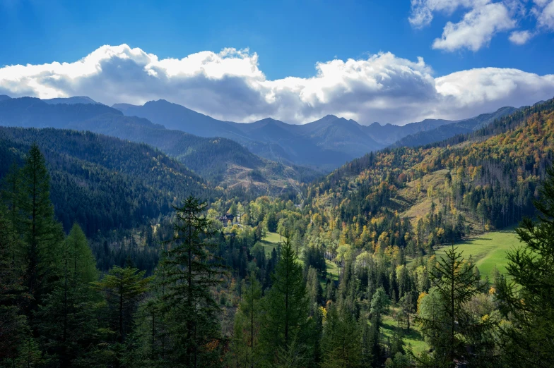 mountains with trees and some clouds in the sky