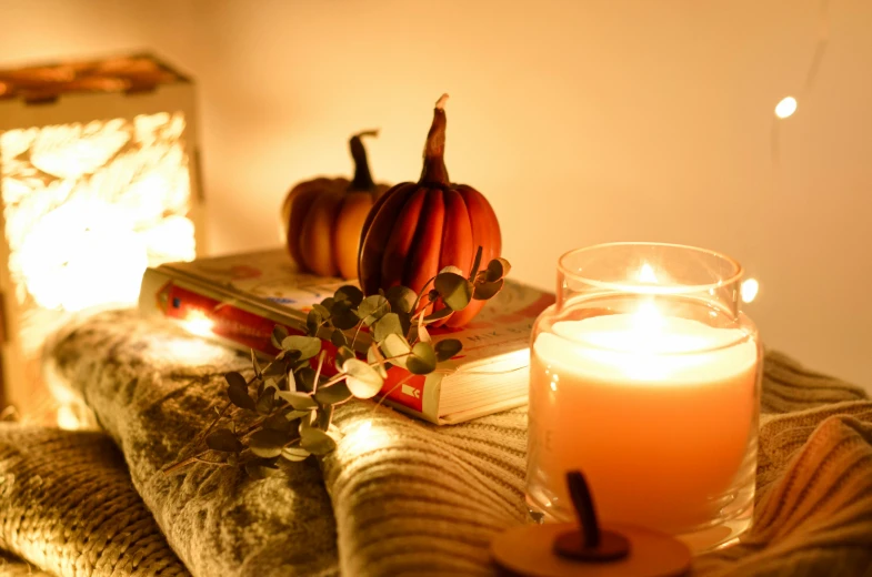 a candle, books and some pumpkins sit on a blanket