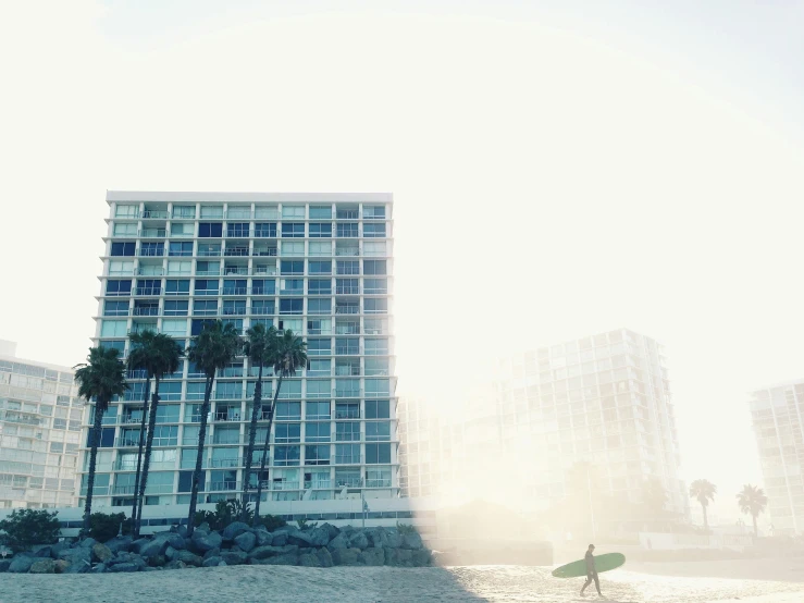 a lone person on a beach with a surfboard