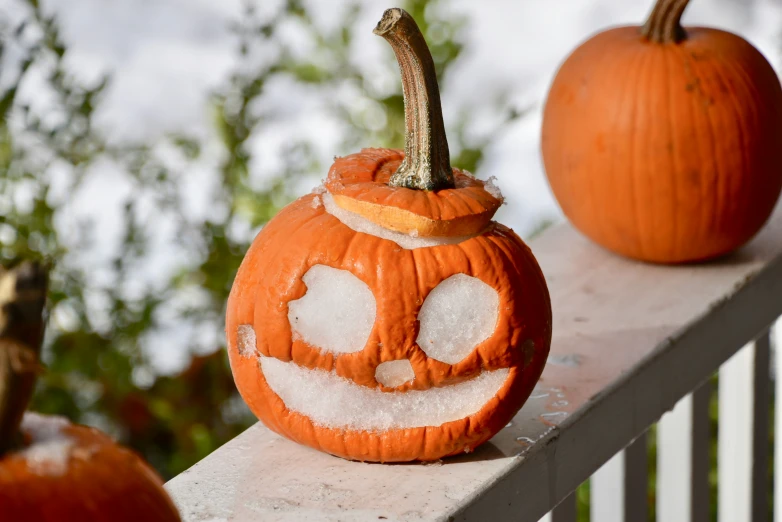 some pumpkins with face holes sitting on a fence