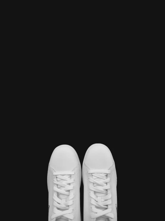 a white pair of sneakers is shown against a black background