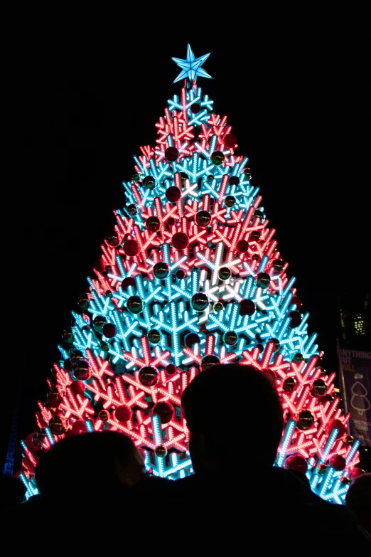 a giant christmas tree in the middle of a dark area