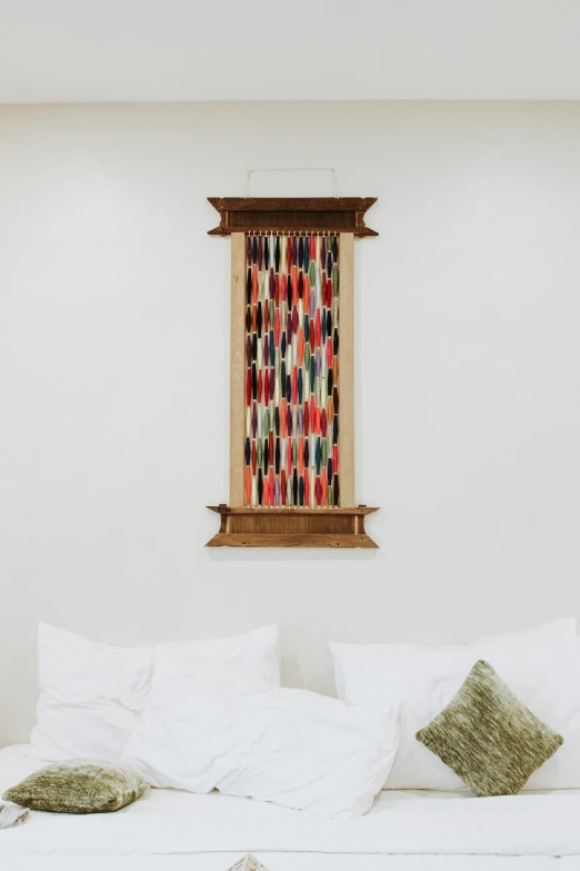 a room with pillows and a painting hanging above the bed