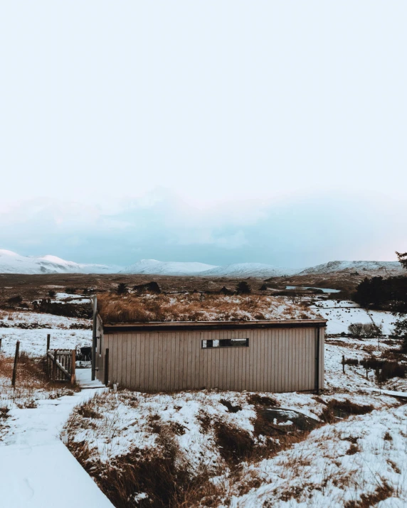 this is a pograph looking from a small building to a snow covered field