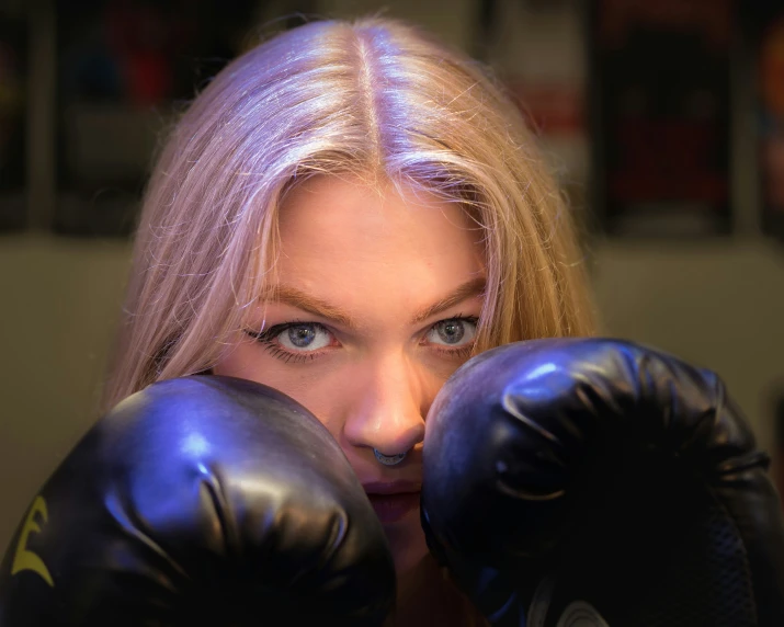 a girl with her eyes behind black boxing gloves