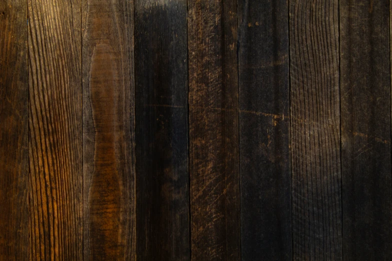 a brown teddy bear is laying next to a black wood surface