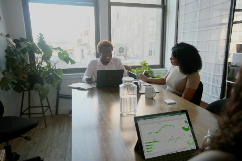 three woman are sitting around a table in a large office