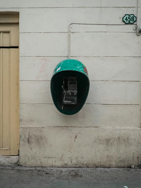 a wall mounted public phone hanging on the side of a building