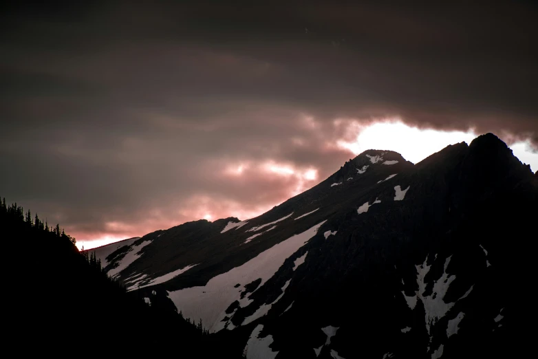 the sun is coming through the clouds behind the mountains