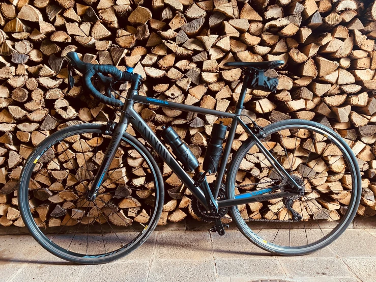 there is a blue bike against a pile of wood