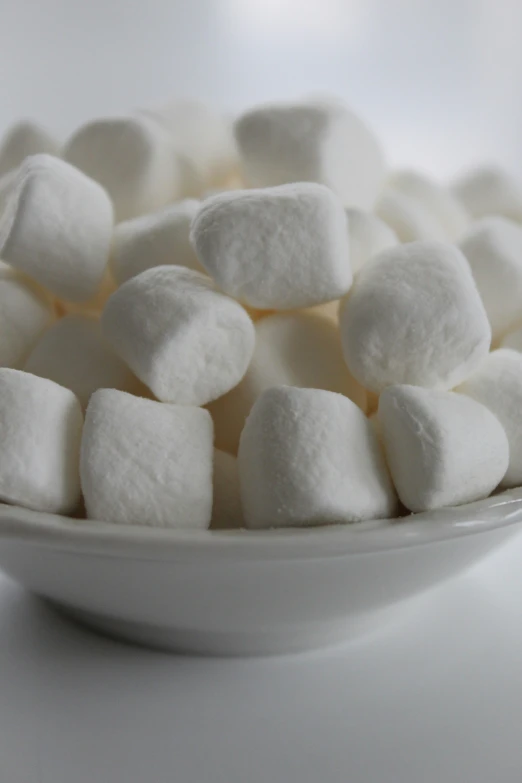 a white bowl full of marshmallows is sitting on the counter
