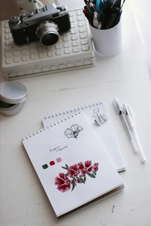 a pen a camera and flowers on a table