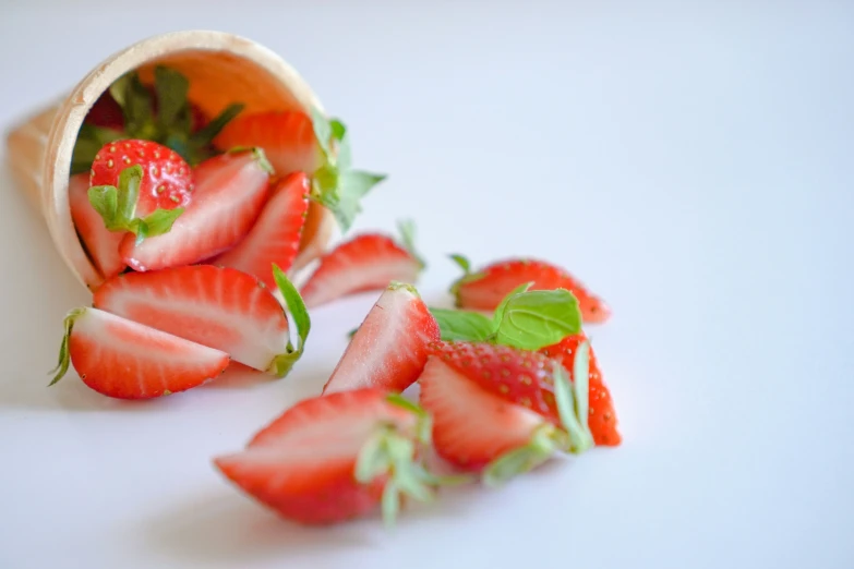 sliced and halved strawberries are sitting in a cup