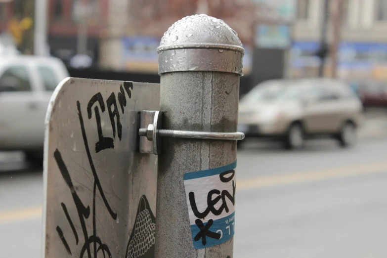 a silver pole with stickers on it sitting in the street