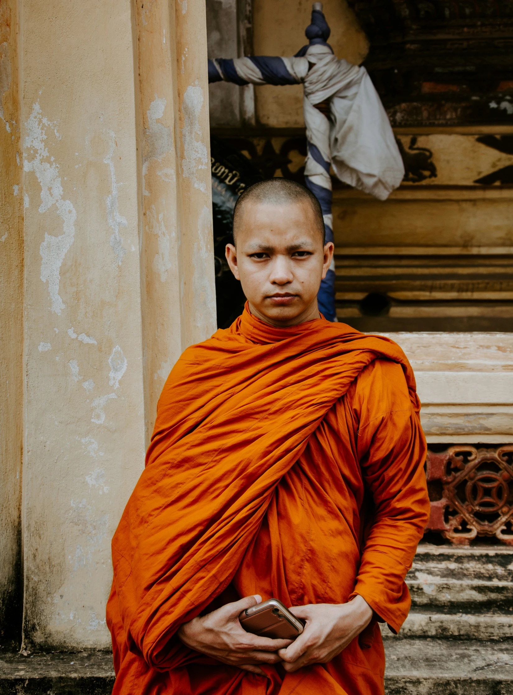 a man in an orange robe and hat standing next to pillars