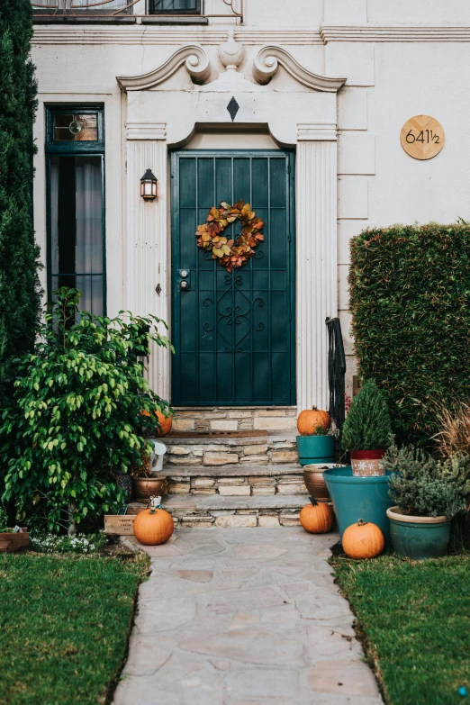 this front door is flanked by pumpkins on each step