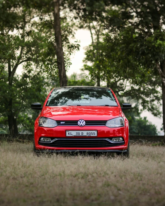 a red car sits in the grass near some trees