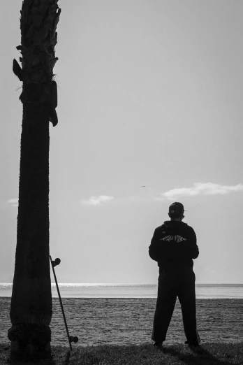 a man standing next to a tree and water