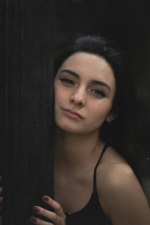 woman in black shirt looking out window with her hand on a window sill