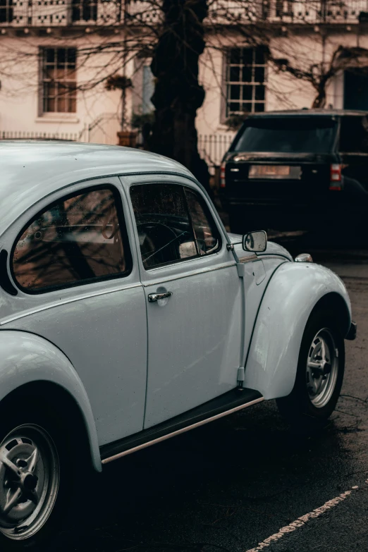 an old volkswagen beetle parked near a tall building