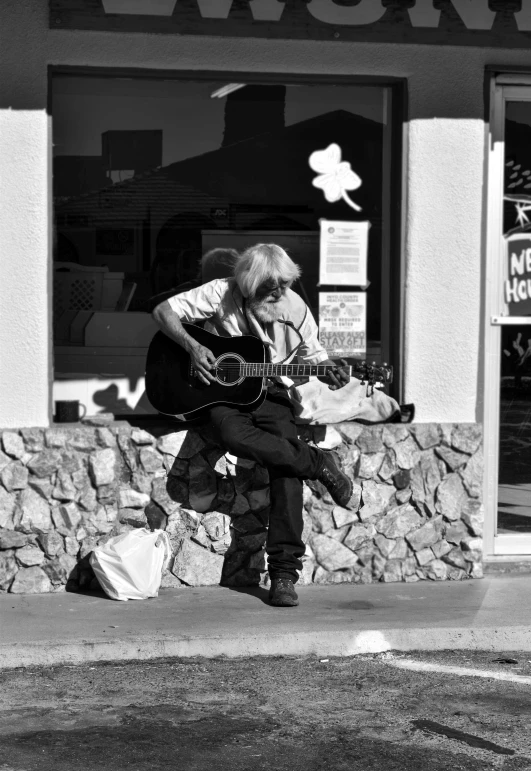 a man that is sitting down with a guitar