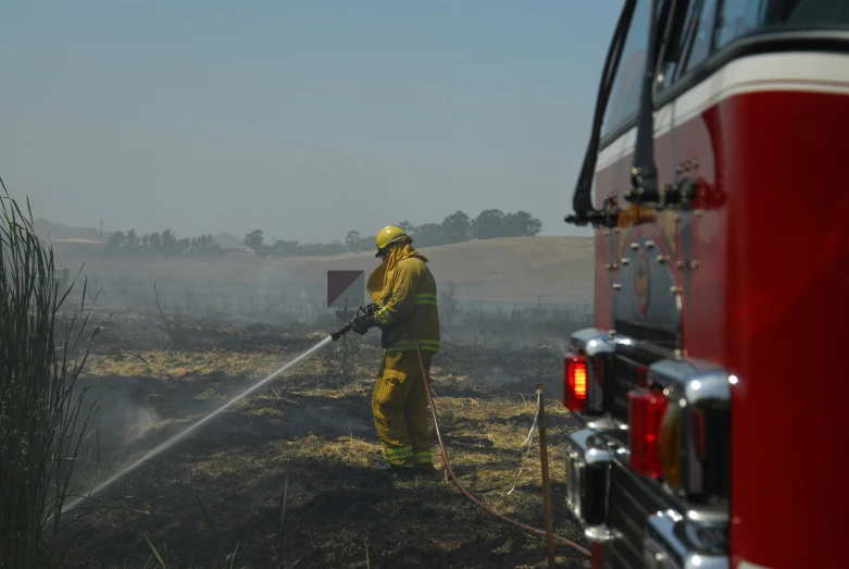 two firemen standing next to each other with a hose on a field